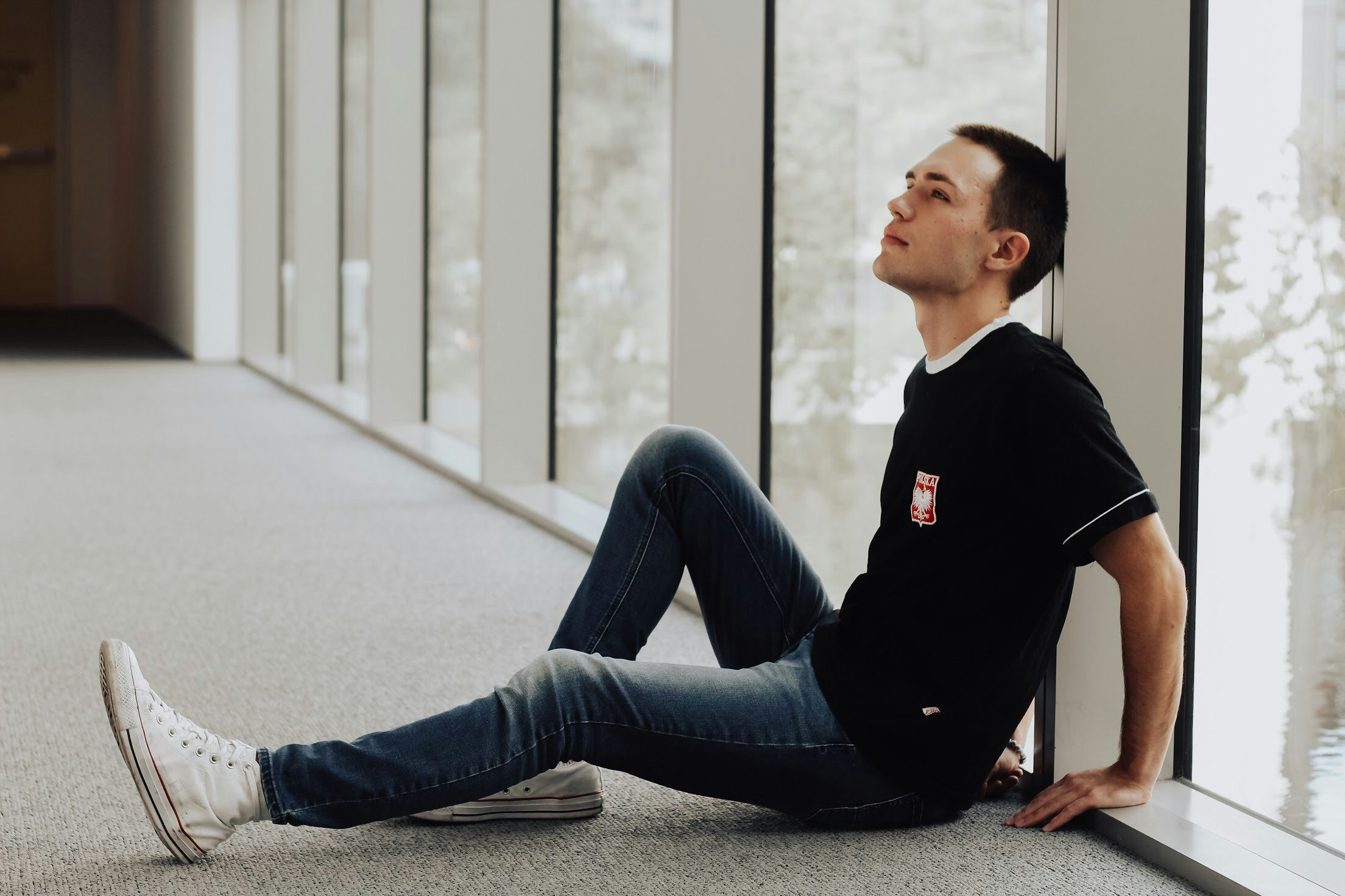 man sitting and leaning on white pillar beside window panel